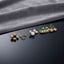 Gold Green Floral Enamel Pearl CZ 4-Pair Stud Earring Set flat lay on black mirror surface with grey fabric backdrop showing gold double ball studs pink coral tulip enamel studs with green leaf white CZ pearl drop studs and large green square enamel stud with pearl row red flower and green clover CZ cluster with mirror reflections below