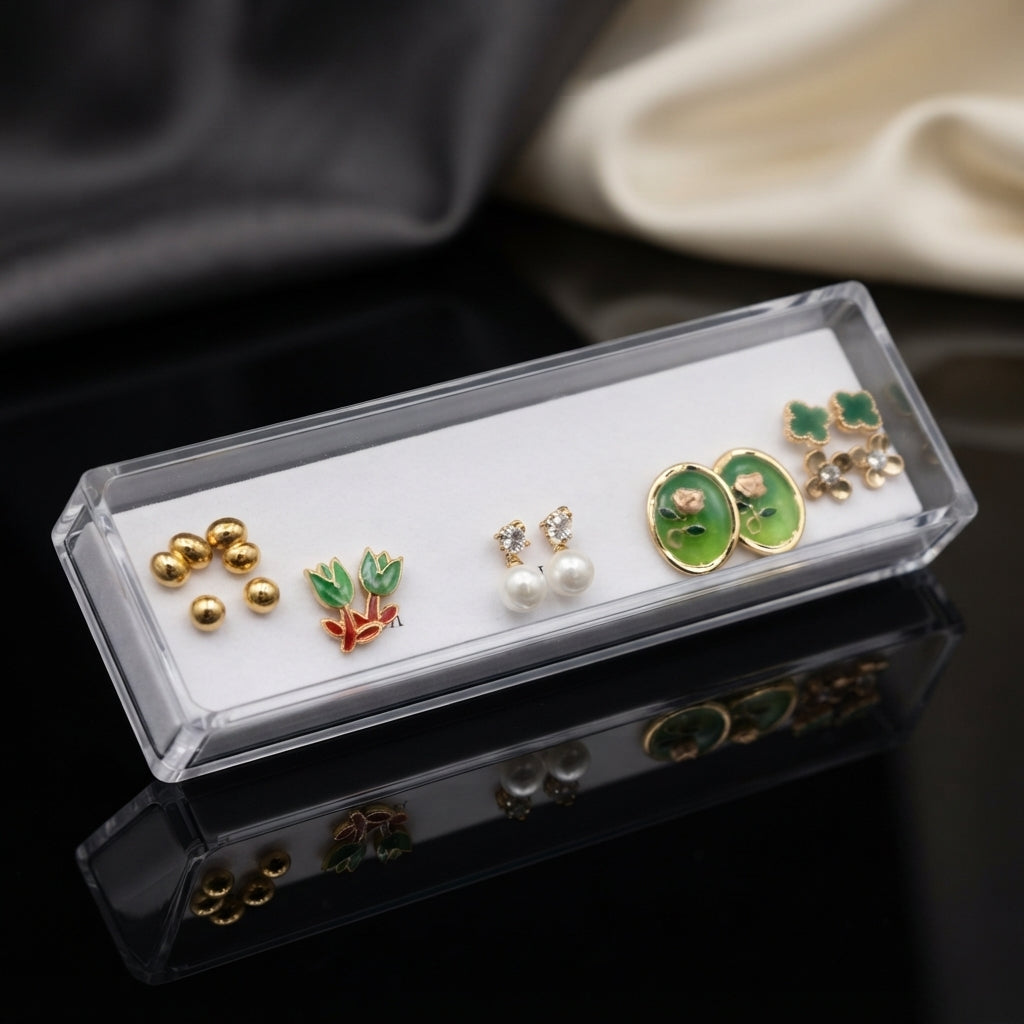 Gold Green Tulip Oval Floral Pearl Clover 5-Pair Stud Earring Set displayed in open clear acrylic gift box on black mirror surface with grey and cream fabric backdrop showing all five pairs on white velvet insert with mirror reflection below