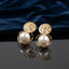 Gold Hammered Disc and Floating Pearl Open Orbit Drop Earrings pair standing on dark grey mirror surface with deep navy blue velvet backdrop showing 18K warm yellow gold-tone hammered textured disc top with short wire connector and open circular orbit frame cradling large floating white simulated pearl with mirror reflection below