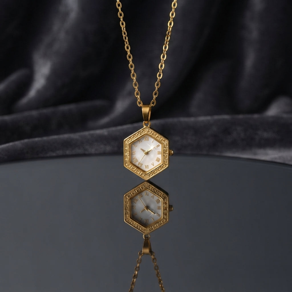 Gold Hexagon Greek Key Watch-Face Pendant Necklace in 18K gold-tone PVD stainless steel on dark grey mirror surface with dark silk backdrop showing bold hexagon pendant with continuous Greek key meander engraved border and decorative white Roman numeral watch-face dial sticker on slim gold cable chain with mirror reflection below