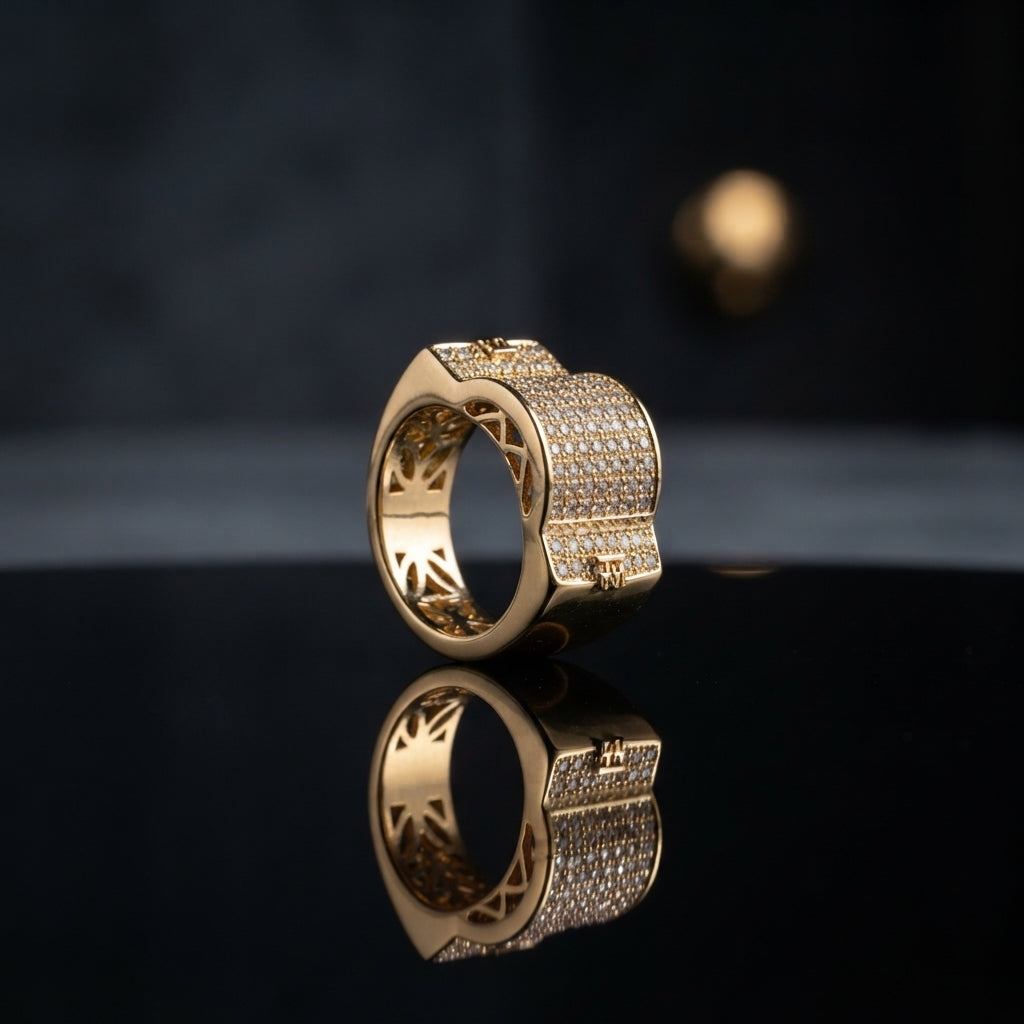 Gold Iced Out CZ Micro-Pavé Wide Band Filigree Statement Ring — 22K gold-tone wide luxury band ring with fully iced out dense round white CZ micro-pavé raised square top and open sunburst geometric filigree cutout inner band, dramatic dark mirror surface with spotlight backdrop editorial