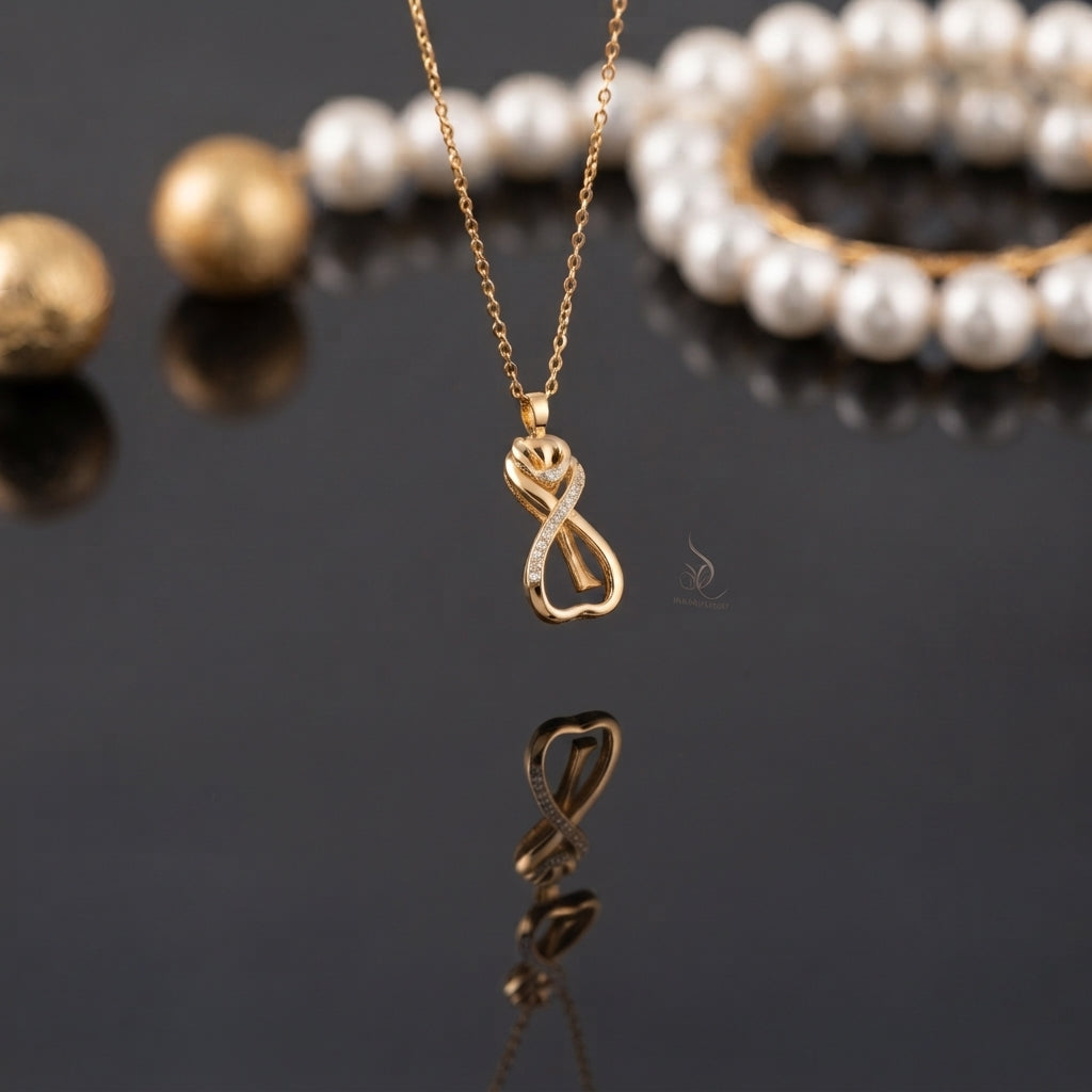 Gold Infinity Heart Rose CZ Pendant Necklace in 18K gold-tone plating on dark grey mirror surface with pearl bracelet and gold sphere backdrop showing delicate fine cable chain with 3D sculptural infinity heart rose pendant featuring micro-pave white CZ diagonal row blooming rose top and open heart base loop with mirror reflection below