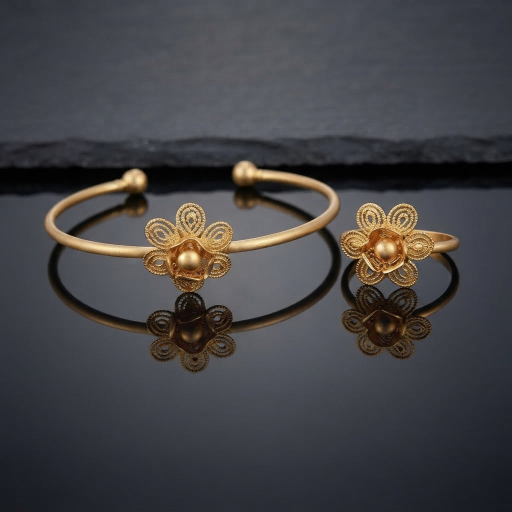 Gold Intricate Filigree Spiral Dome Flower Open Cuff Bangle and Ring Matching Jewelry Set on dark grey glossy surface with charcoal stone backdrop showing 22K warm matte yellow gold-tone open cuff bangle lying flat with matching open adjustable ring standing beside it both featuring 5-petal open filigree spiral scroll flowers with micro-filigree swirl-filled teardrop petals granulation borders and large raised 3D polished dome bud centres with cupped mini-petals with sharp mirror reflections below