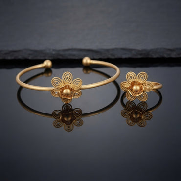 Gold Intricate Filigree Spiral Dome Flower Open Cuff Bangle and Ring Matching Jewelry Set on dark grey glossy surface with charcoal stone backdrop showing 22K warm matte yellow gold-tone open cuff bangle lying flat with matching open adjustable ring standing beside it both featuring 5-petal open filigree spiral scroll flowers with micro-filigree swirl-filled teardrop petals granulation borders and large raised 3D polished dome bud centres with cupped mini-petals with sharp mirror reflections below