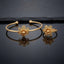 Gold Intricate Filigree Spiral Dome Flower Open Cuff Bangle and Ring Matching Jewelry Set on dark grey glossy surface with charcoal stone backdrop showing 22K warm matte yellow gold-tone open cuff bangle lying flat with matching open adjustable ring standing beside it both featuring 5-petal open filigree spiral scroll flowers with micro-filigree swirl-filled teardrop petals granulation borders and large raised 3D polished dome bud centres with cupped mini-petals with sharp mirror reflections below