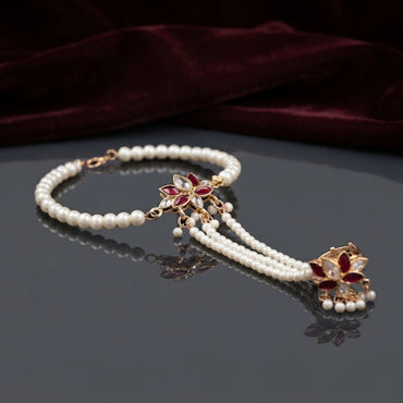 Gold Kundan Lotus Pearl Hath Phool Hand Harness Bracelet Ring in White Ivory variant worn by Pakistani female model in blush pink bridal outfit showing white MOP kundan lotus hath phool with fine pearl bracelet and 3 strand seed pearl hand chain connecting to finger ring in luxury bridal boutique backdrop