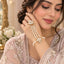 Gold Kundan Lotus Pearl Hath Phool Hand Harness Bracelet Ring in Ruby Red variant flat lay on grey mirror surface with burgundy velvet backdrop showing single strand fine pearl bracelet with ruby red enamel kundan lotus flower focal and 3 parallel seed pearl strands to matching smaller ruby red kundan lotus finger ring with pearl drops in antique gold tone