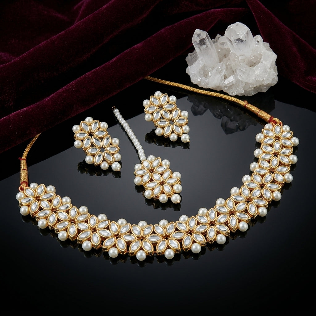 Gold-Tone Kundan Marquise & Pearl Choker, Earrings & Maang Tikka Bridal Set flat lay on black mirror surface with white quartz crystal cluster and deep burgundy velvet fabric backdrop