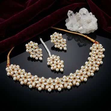Gold-Tone Kundan Marquise & Pearl Choker, Earrings & Maang Tikka Bridal Set flat lay on black mirror surface with white quartz crystal cluster and deep burgundy velvet fabric backdrop