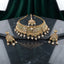 Gold Kundan Meenakari Pearl Drop Choker Necklace Earrings & Maang Tikka Bridal Set on dark grey marble surface with green velvet drape backdrop