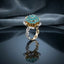 Gold Lotus Flower Cluster CZ Dome Cocktail Ring in Teal — 22K gold-tone lotus flower basket ring with dense teal paraiba CZ dome cluster crown, white CZ pavé petal halo, and split pavé shank, on dark mirror surface with navy velvet backdrop