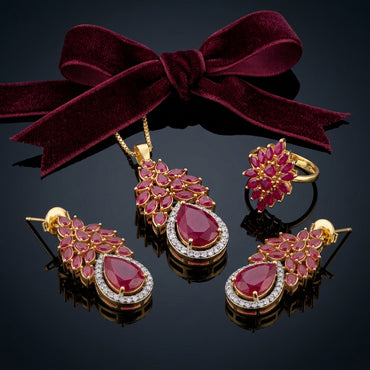 Gold-Tone Marquise & Pear CZ Sunburst Floral Crown Pavé Halo Pendant Necklace Earrings & Ring Jewelry Set in Ruby Red on dark mirror surface with burgundy velvet bow ribbon backdrop