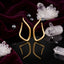 Gold-Tone Matte Sculptural Tulip Flame Open Teardrop Wishbone Long Drop Earrings on black mirror surface with white crystal quartz clusters, black hematite beads and deep burgundy velvet backdrop