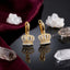Gold-Tone Micro-Pavé CZ 3D Royal Crown Pendant Huggie Hoop Drop Statement Earrings on black mirror surface with white crystal quartz clusters and deep burgundy velvet backdrop