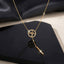Gold Micro Pavé CZ Heartbeat Circle Lariat Bar Necklace flat lay on black glossy surface with dark silk backdrop showing fully CZ-encrusted open circle pendant with EKG heartbeat wave motif on gold-tone box chain with Y-drop lariat tail and polished gold bar charm drop and mirror reflection below