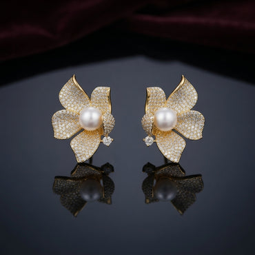 Gold-Tone Micro-Pavé CZ Orchid Flower Pearl Center Statement Stud Earrings on dark mirror surface with deep burgundy velvet backdrop