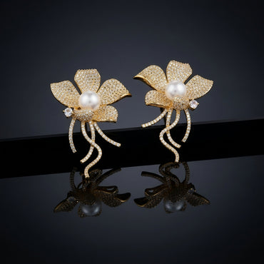 Gold-Tone Micro-Pavé CZ Wild Orchid Pearl Center & Pavé Tendril Stem Statement Earrings on black mirror surface with dark background