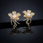 Gold-Tone Micro-Pavé CZ Wild Orchid Pearl Center & Pavé Tendril Stem Statement Earrings on black mirror surface with dark background