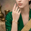 Gold Minimalist Satellite Bead Hand Chain Bracelet Ring Set in 18K gold-tone plating worn on hand of model wearing green banarsi saree with gold border showing delicate fine cable chain bracelet at wrist with Y-junction splitting into two chains across back of hand with small round gold satellite beads at intervals connected to thin finger ring with brass vessels and warm beige backdrop