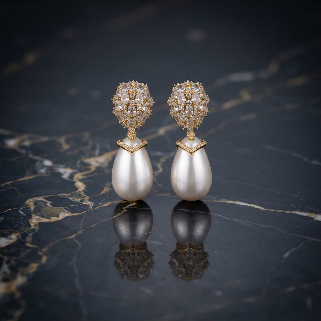Gold-Tone Mixed-Cut CZ Dome Cluster Cap & Baroque Pearl Teardrop Drop Earrings on dark marble surface with navy blue silk fabric backdrop