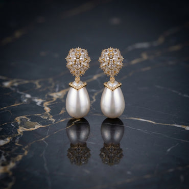 Gold-Tone Mixed-Cut CZ Dome Cluster Cap & Baroque Pearl Teardrop Drop Earrings on dark marble surface with navy blue silk fabric backdrop