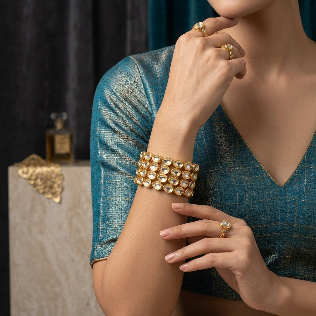 Gold Mixed-Shape Kundan Polki Teardrop Oval Full-Bezel Slim Bangle Set of 4 worn stacked on model wrist in teal tissue silk blouse with marble and dark backdrop showing wide cuff stack of four slim bangles with alternating teardrop and oval flat-cut CZ kundan polki stones in antique gold bezel settings