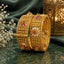 Gold-Tone Mughal Kundan Polki Flower & Ruby CZ Grid Panel Wide Kada Bangle Set of 2 on green marble surface with gold lantern and baby's breath flowers backdrop