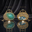 Gold Mughal Minaudère Round Teal Peacock Bead Amazonite Pearl Clutch Bag — front: gold zardozi leaf-scale border, dense iridescent teal peacock bead field, large pale mint amazonite freeform pear cabochon center; back: gold zardozi tile field, navy blue bead crescent arc, baroque pearls, gold botanical vine; dark silk backdrop with mirror reflection