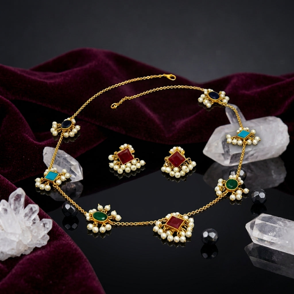 Gold-Tone Multicolour Gemstone & Seed Pearl Fringe Station Chain Necklace & Stud Earrings Set flat lay on dark mirror surface with white crystal quartz clusters, black faceted beads and deep burgundy velvet backdrop