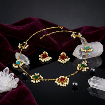 Gold-Tone Multicolour Gemstone & Seed Pearl Fringe Station Chain Necklace & Stud Earrings Set flat lay on dark mirror surface with white crystal quartz clusters, black faceted beads and deep burgundy velvet backdrop