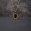 Gold Oval Greek Key Black Dial Watch-Face Pendant Necklace in 18K gold-tone PVD stainless steel hanging on grey marble textured backdrop showing rounded rectangle oval cushion pendant with continuous Greek key meander engraved border and decorative black Roman numeral watch-face dial sticker with gold-tone hands on slim gold cable paperclip link chain