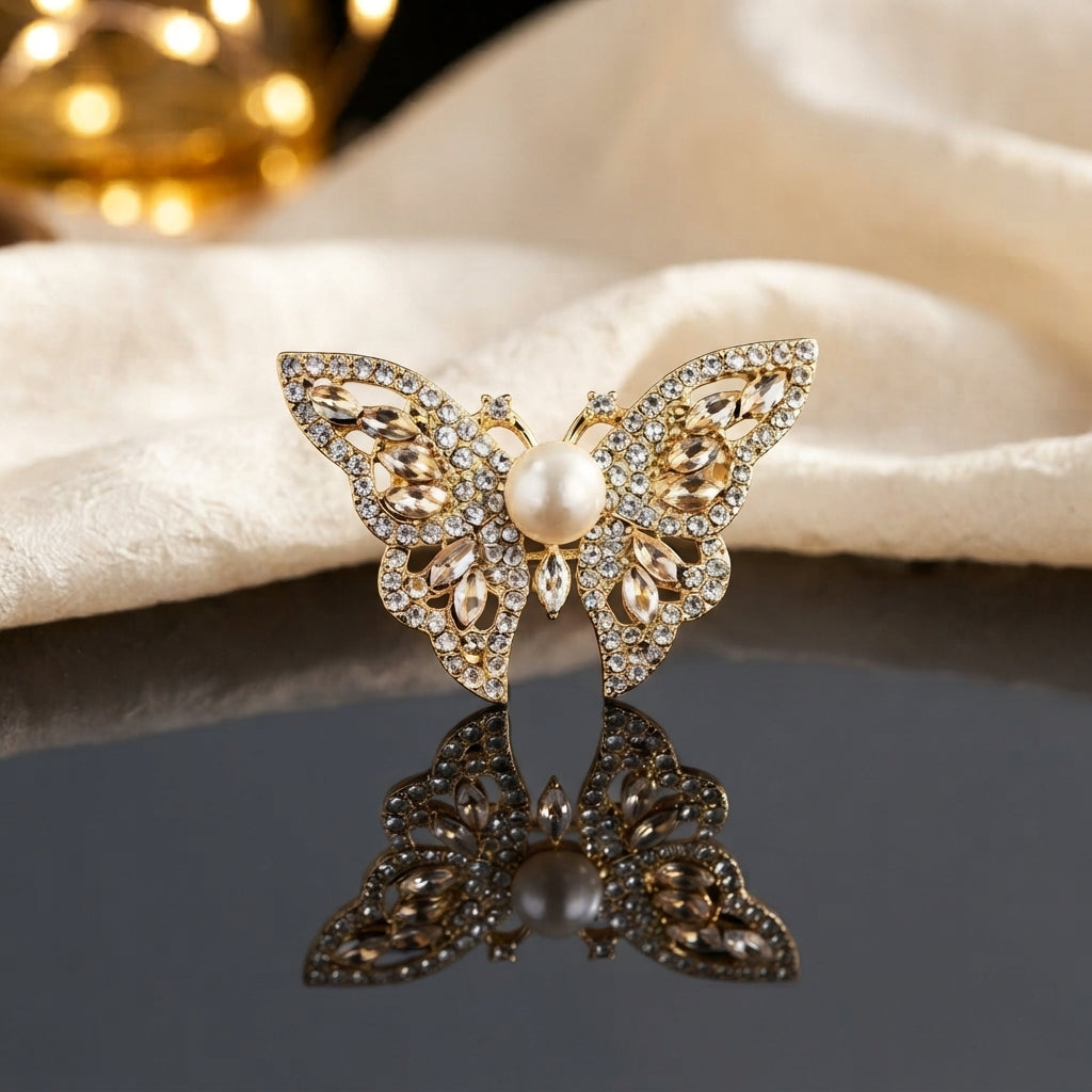 Gold Pearl Butterfly Crystal Brooch in Rose Pink on dark grey mirror surface with cream fabric backdrop showing large butterfly brooch with open filigree gold wings dense micro-pave white CZ border rose pink marquise crystal wing stones and large faux pearl centre with mirror reflection below