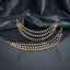 Gold Pearl Drop Multi-Strand Sahara Earrings Pair product shot on dark grey mirror surface with blue silk fabric backdrop showing two 4-strand cascading crescent swag gold cable chain earrings with evenly spaced round faux pearl drops and hook loop attachment ends with mirror reflections below