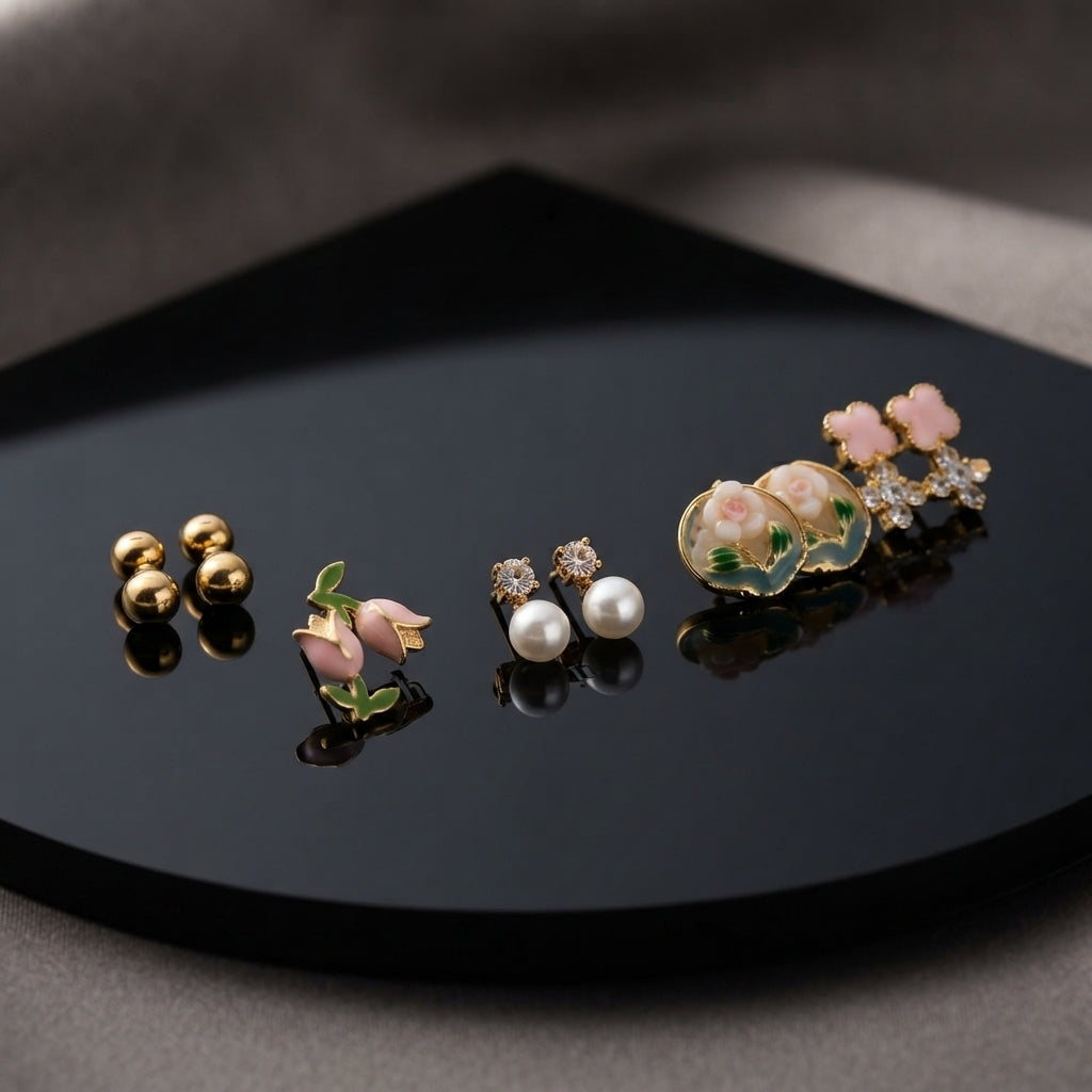 Gold Pink Floral Enamel Pearl CZ 4-Pair Stud Earring Set displayed in open clear acrylic gift box on black mirror surface with grey fabric backdrop showing all four pairs arranged on white velvet insert
