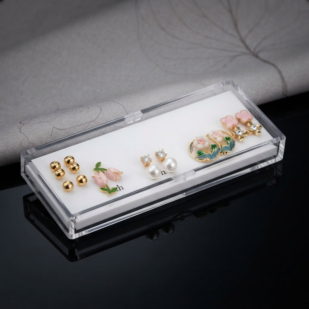 Gold Pink Floral Enamel Pearl CZ 4-Pair Stud Earring Set flat lay on black mirror surface showing gold double ball studs pink tulip enamel studs with green leaf CZ pearl drop studs and large gold hoop with pink floral enamel scene and pink flower cluster CZ top with mirror reflections below