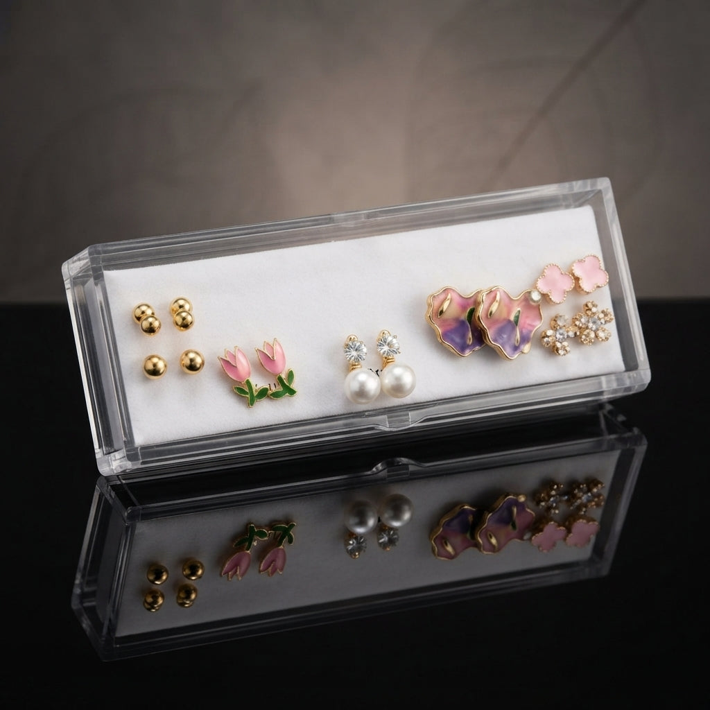 Gold Pink Purple Floral Enamel Pearl CZ 4-Pair Stud Earring Set flat lay on black velvet tray with grey fabric backdrop showing gold double ball studs pink tulip enamel studs white CZ pearl drop studs and large purple iridescent floral enamel petal stud with pink clover and CZ snowflake cluster with mirror reflections below