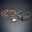 Gold Polished Star Pendant Necklace Cuff Bangle Earrings Set — 3-piece all-gold minimalist set of fine cable chain with large polished 5-point star pendant, open ball-end cuff bangle with center star and bead accents, and matching small gold star stud earrings, luxury flat-lay on dark mirror surface with charcoal silk backdrop