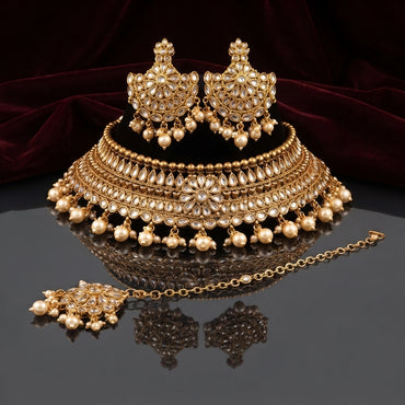 Gold Polki Kundan and Pearl Grand Choker Bridal Set flat lay on dark mirror surface with burgundy velvet backdrop showing 3-piece bridal set with grand wide choker necklace featuring continuous teardrop polki row and large Mughal floral medallions in dense marquise and oval white polki kundan with cream pearl fringe drops with matching shield chandelier earrings and maang tikka with mirror reflection