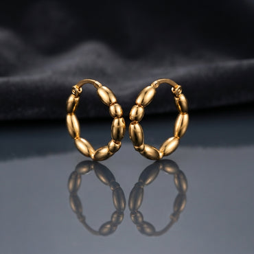 Gold PVD Stainless Steel Chunky Oval Bubble Bead Hoop Earrings pair leaning against each other on dark mirror surface with charcoal slate satin backdrop showing 18K gold PVD coated stainless steel hoops with 7 to 8 large puffy oval barrel beads linked in continuous circle with hinged click closure and sharp mirror reflection below