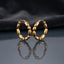 Gold PVD Stainless Steel Chunky Oval Bubble Bead Hoop Earrings pair leaning against each other on dark mirror surface with charcoal slate satin backdrop showing 18K gold PVD coated stainless steel hoops with 7 to 8 large puffy oval barrel beads linked in continuous circle with hinged click closure and sharp mirror reflection below