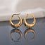 Gold PVD Stainless Steel Crescent Basket Hoop Earrings with Ribbed Knot Accent pair standing side by side on dark grey mirror surface with soft warm cream ivory fabric backdrop showing 18K gold PVD coated stainless steel wide crescent basket hoops with graduated puffy crescent body and decorative ribbed rope-cut knot wrap accent at widest point mirror-polish finish with French lever closure and sharp mirror reflection below