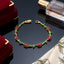 Gold-Tone Multicolor CZ Oval & Marquise Vine Wave Tennis Bracelet on dark reflective surface with gold satin ribbon and perfume bottle backdrop