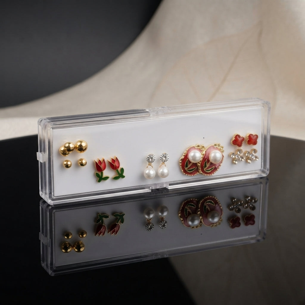 Gold Red Tulip Floral Enamel Pearl CZ 4-Pair Stud Earring Set flat lay on black marble surface with beige backdrop showing gold double ball studs red crimson tulip enamel studs with green leaf silver CZ pearl drop studs and large red burgundy enamel oval stud with two large faux pearls green leaf detail red clover and silver CZ snowflake cluster with mirror reflections below