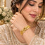 Gold Ribbed Braided Infinity Link Wide Cuff Bangle worn on wrist of Pakistani female model in champagne ivory heavily embroidered bridal lehenga with upswept hair in luxury backdrop with white flowers and candles showing wide rigid cuff bangle with continuous repeating braided infinity link pattern in high-polish 22K gold-tone with fine ribbed texture