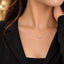 Gold Round Brilliant CZ Solitaire Floating Pendant Necklace close-up worn by model in black blazer with gold bokeh backdrop