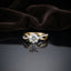 Gold Round CZ Solitaire Infinity Twist Crossover Bridal Engagement Ring on dark grey mirror surface with dark brown velvet drape backdrop