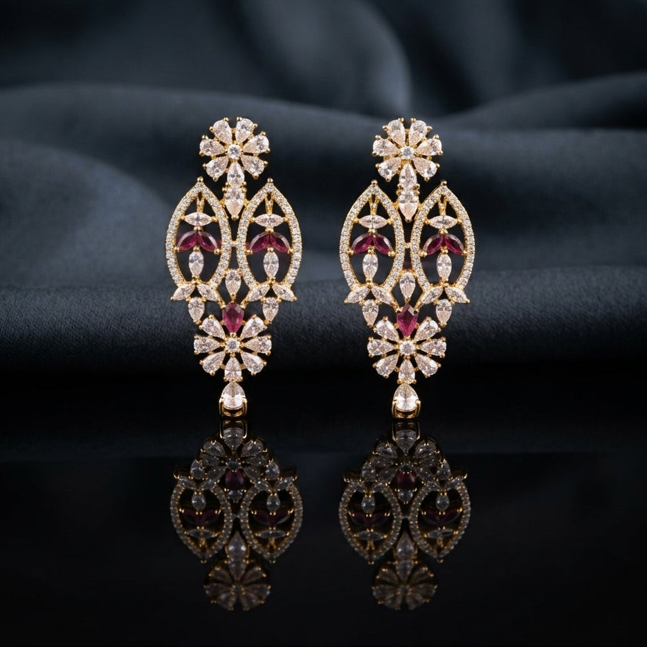 Gold Ruby and White CZ Marquise Floral Oval Lattice Drop Earrings — 18-22K gold-tone statement bridal earrings with pear CZ daisy floral stud open oval marquise trellis lattice body with ruby CZ intersection points and marquise white CZ windows and small daisy pear CZ drop displayed on dark black mirror surface with charcoal satin backdrop