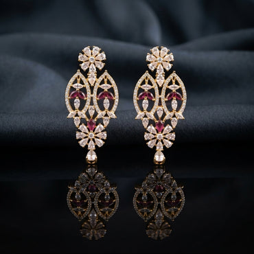 Gold Ruby and White CZ Marquise Floral Oval Lattice Drop Earrings — 18-22K gold-tone statement bridal earrings with pear CZ daisy floral stud open oval marquise trellis lattice body with ruby CZ intersection points and marquise white CZ windows and small daisy pear CZ drop displayed on dark black mirror surface with charcoal satin backdrop