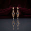 Gold Sapphire Blue CZ Filigree Chandelier Drop Earrings — 18-22K gold-tone Art Deco bridal chandelier earrings with pear CZ halo stud snowflake CZ connector elongated open gold filigree lattice body with sapphire blue pear CZ center focal and single pear CZ halo drop displayed on dark grey mirror surface with burgundy velvet backdrop