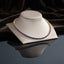 Gold Sapphire Blue Round CZ Tennis Necklace on cream leather jewelry bust with dark brown velvet drape backdrop
